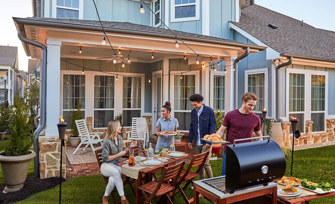 Friends gathered on a string-lit backyard patio at dusk